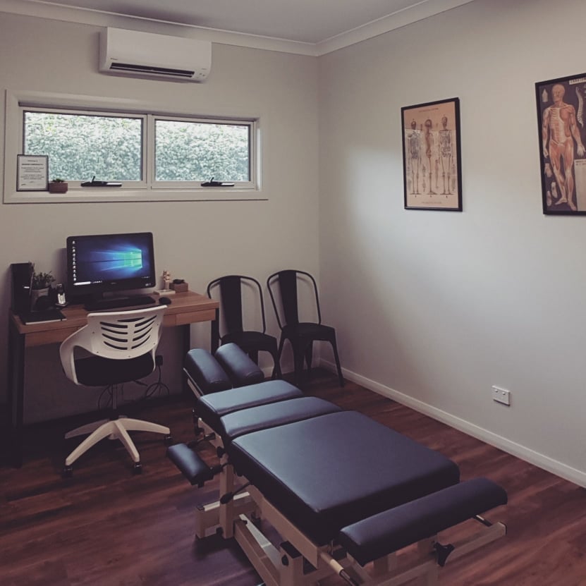 Treatment room at Basham Chiropractic, Nowra — adjusting bench, anatomy charts and consultation desk